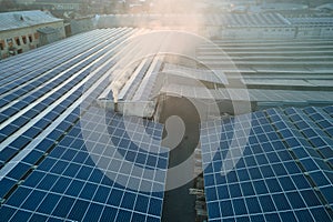 Aerial view of blue photovoltaic solar panels mounted on industrial building roof for producing green ecological