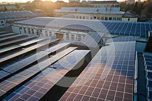 Aerial view of blue photovoltaic solar panels mounted on industrial building roof for producing green ecological