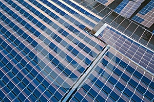 Aerial view of blue photovoltaic solar panels mounted on industrial building roof for producing green ecological