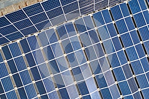 Aerial view of blue photovoltaic solar panels mounted on industrial building roof for producing green ecological