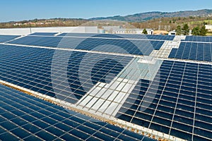 Aerial view of blue photovoltaic solar panels mounted on industrial building roof for producing green ecological