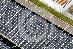 Aerial view of blue photovoltaic solar panels mounted on industrial building roof for producing green ecological