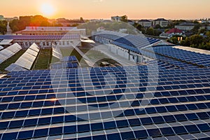 Aerial view of blue photovoltaic solar panels mounted on industrial building roof for producing green ecological