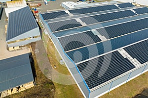 Aerial view of blue photovoltaic solar panels mounted on industrial building roof for producing green ecological