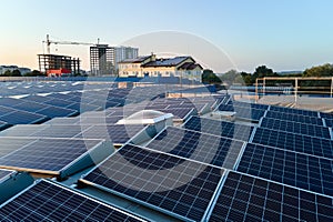 Aerial view of blue photovoltaic solar panels mounted on industrial building roof for producing green ecological