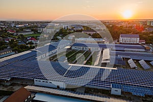 Aerial view of blue photovoltaic solar panels mounted on industrial building roof for producing green ecological