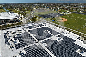 Aerial view of blue photovoltaic solar panels mounted on industrial building roof for producing green ecological