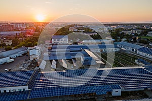 Aerial view of blue photovoltaic solar panels mounted on industrial building roof for producing green ecological