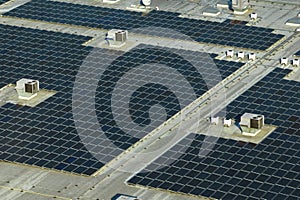 Aerial view of blue photovoltaic solar panels mounted on industrial building roof for producing green ecological