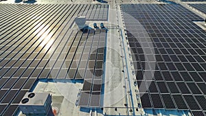 Aerial view of blue photovoltaic solar panels mounted on industrial building roof for producing green ecological