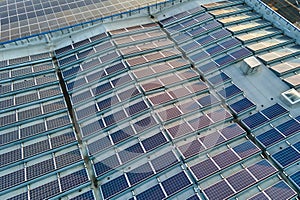 Aerial view of blue photovoltaic solar panels mounted on industrial building roof for producing green ecological