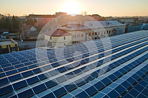 Aerial view of blue photovoltaic solar panels mounted on industrial building roof for producing green ecological