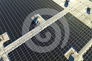 Aerial view of blue photovoltaic solar panels mounted on industrial building roof for producing green ecological