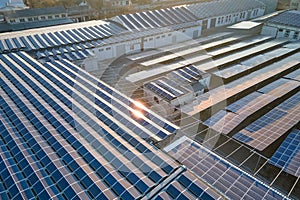 Aerial view of blue photovoltaic solar panels mounted on industrial building roof for producing green ecological