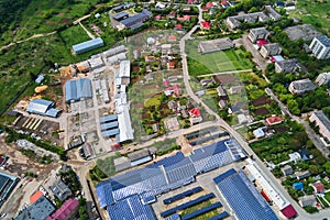 Aerial view of blue photovoltaic solar panels mounted on industrial building roof for producing green ecological electricity.