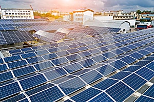 Aerial view of blue photovoltaic solar panels mounted on industrial building roof for producing green ecological electricity.