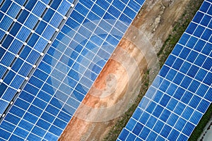 Aerial view of blue photovoltaic solar panels mounted on industrial building roof for producing green ecological electricity.