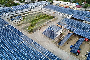 Aerial view of blue photovoltaic solar panels mounted on industrial building roof for producing green ecological electricity.