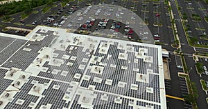 Aerial view of blue photovoltaic solar panels mounted on shopping mall building roof for producing green ecological