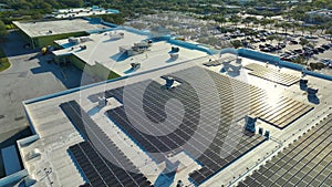 Aerial view of blue photovoltaic solar panels mounted on shopping mall building roof for producing green ecological