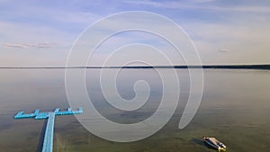 Aerial view of blue plastic pier with fishing boats. Small boats floating on the lake near the pier. Relax concept for design