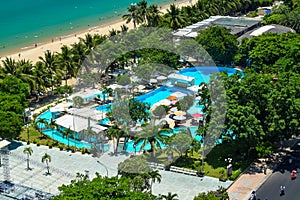 Aerial view on blue pool and tropical beach with green palms on resort