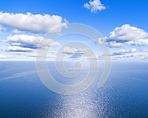 Aerial view of a blue sea water background and sun reflections. Aerial flying drone view. Waves water surface texture on sunny tro