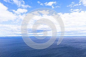 Aerial view of a blue sea water background and sun reflections. Aerial flying drone view. Waves water surface texture on sunny tro