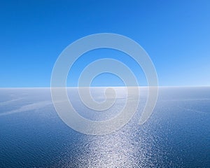 Aerial view of a blue sea water background and sun reflections. Aerial flying drone view. Waves water surface texture on sunny tro