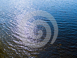 Aerial view of a blue sea water surface background and sun reflections. Aerial flying drone view. Waves water surface texture on s