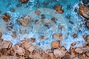 Aerial view of blue sea with waves, rocks, stones in clear water