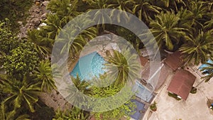 Aerial view blue swimming pool in tropical resort hotel. Drone view tourist hotel with outdoor swimming pool and palm