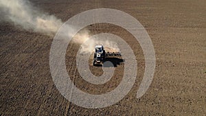 Aerial view of blue tractor with farmer inside plowing on field