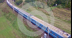 Aerial view of a blue train in rural area. Aerial tracking of a passenger train in the countryside.