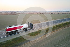 Aerial view of blurred fast moving fuel cargo truck driving on highway hauling goods. Delivery transportation and