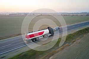 Aerial view of blurred fast moving fuel cargo truck driving on highway hauling goods. Delivery transportation and