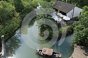 Aerial view of a boat near the wooden pier on the shore in front of a house in China