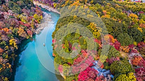 Aerial view boat on the river bring tourist people to enjoy autumn colors along katsura river to Arashiyama mountain area during