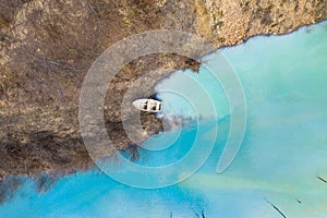 Aerial view of a boat in a turquoise lake contaminated with cyanide photo