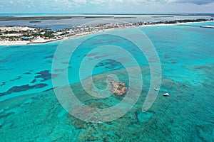 Aerial view of boats anchored off coral rocks with North Bimini in background.