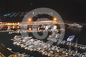Aerial view of boats and beautiful city at night in Sorrento, Italy. Amazing landscape with boats in marina bay, sea, city lights