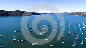 Aerial view of boats moored on Hawkesbury River, Brooklyn, Australia with blue water and headland in background