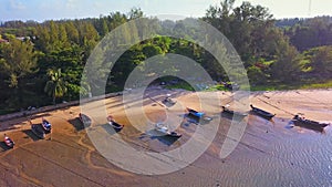 Aerial view of boats with natural forest trees, sand, tropical beach and waves rolling into the shore, Andaman sea, Phuket bay