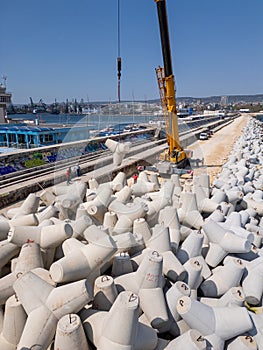 Aerial view of breakwater construction. Crane on a pile of boulders in the sea