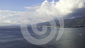 Aerial view of breathtaking blue ocean with small waves on coastal city background and mountains. Concept. Marine