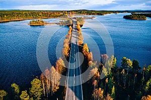 Aerial view of bridge across blue lakes in colorful autumn forest in Finland