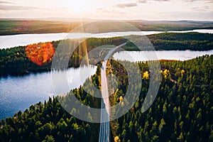 Aerial view of bridge across blue lakes with sun light in colorful autumn forest in Finland