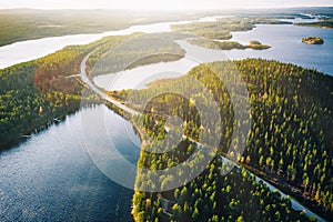 Aerial view of bridge across blue lakes with sun light in colorful autumn forest in Finland