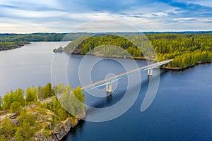 Aerial view of the bridge and island on a blue lake Saimaa. Landscape with drone. Blue lakes, islands and green forests from above