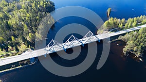 Aerial view on the bridge over the lake and trees in the forest on the shore.